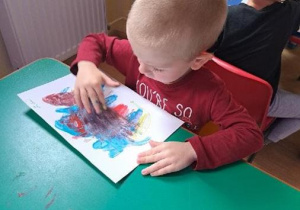 Chłopiec maluje palcami nt. dowolny.
